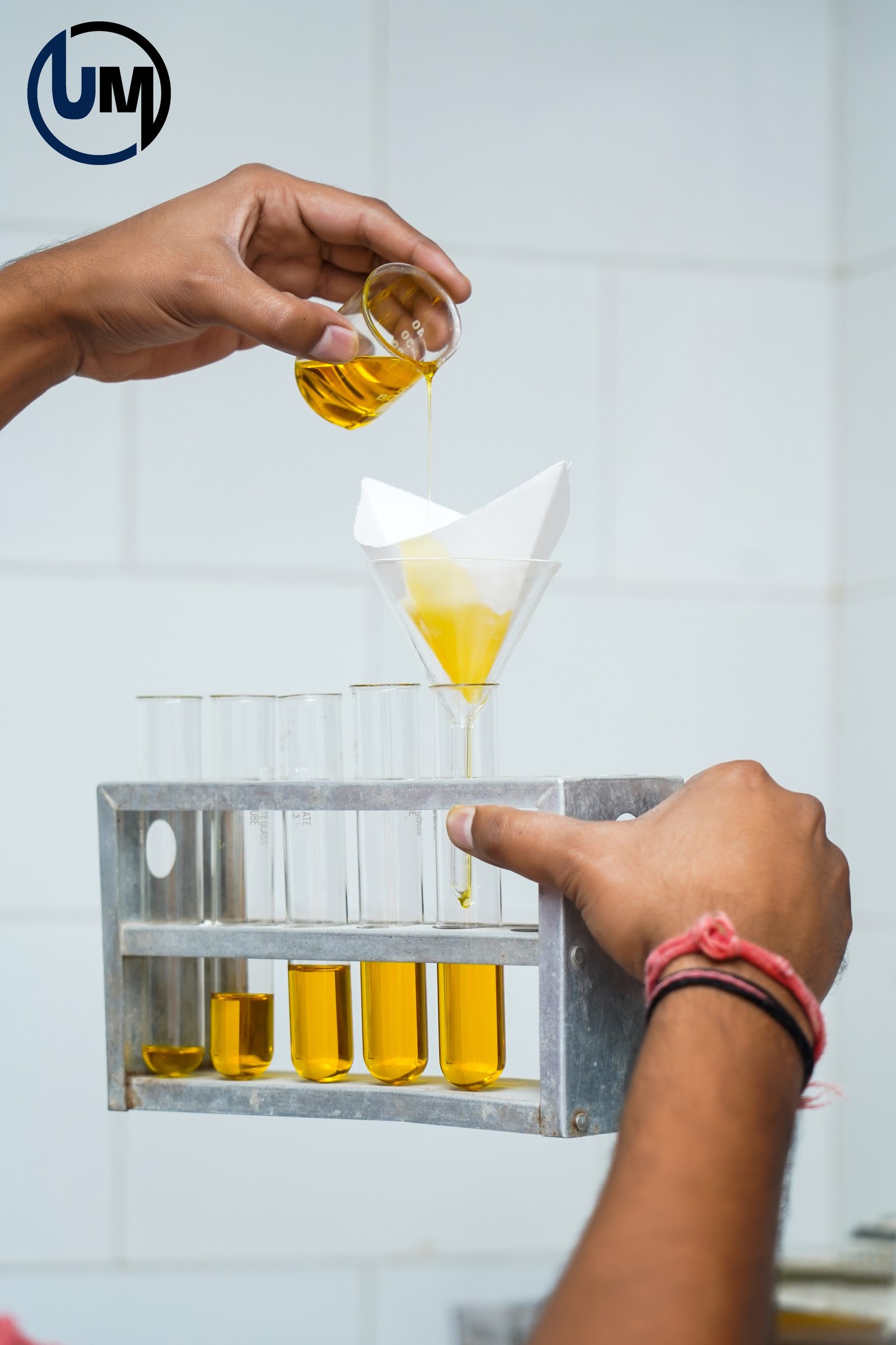 QC filtration process — hands pouring oil through filter funnel